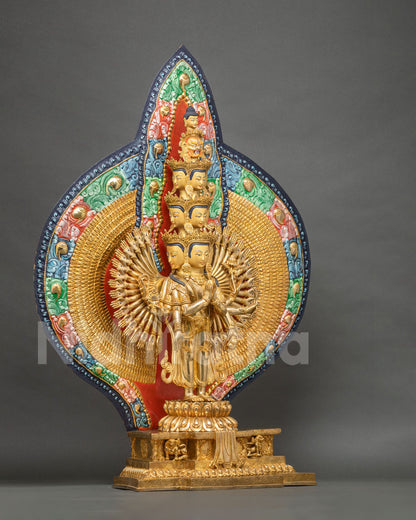 Side-angle view of 1000-armed Chenrezig statue on lotus base with painted gold backdrop