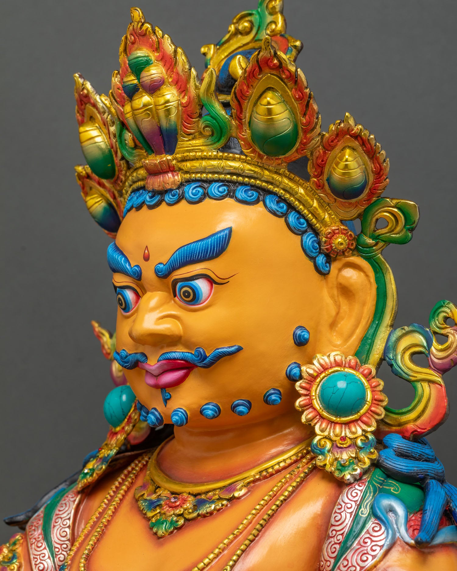 Side Close Up Face of Yellow Dzambhala Statue with Blue Eyebrows Mustache and Turquoise Crown