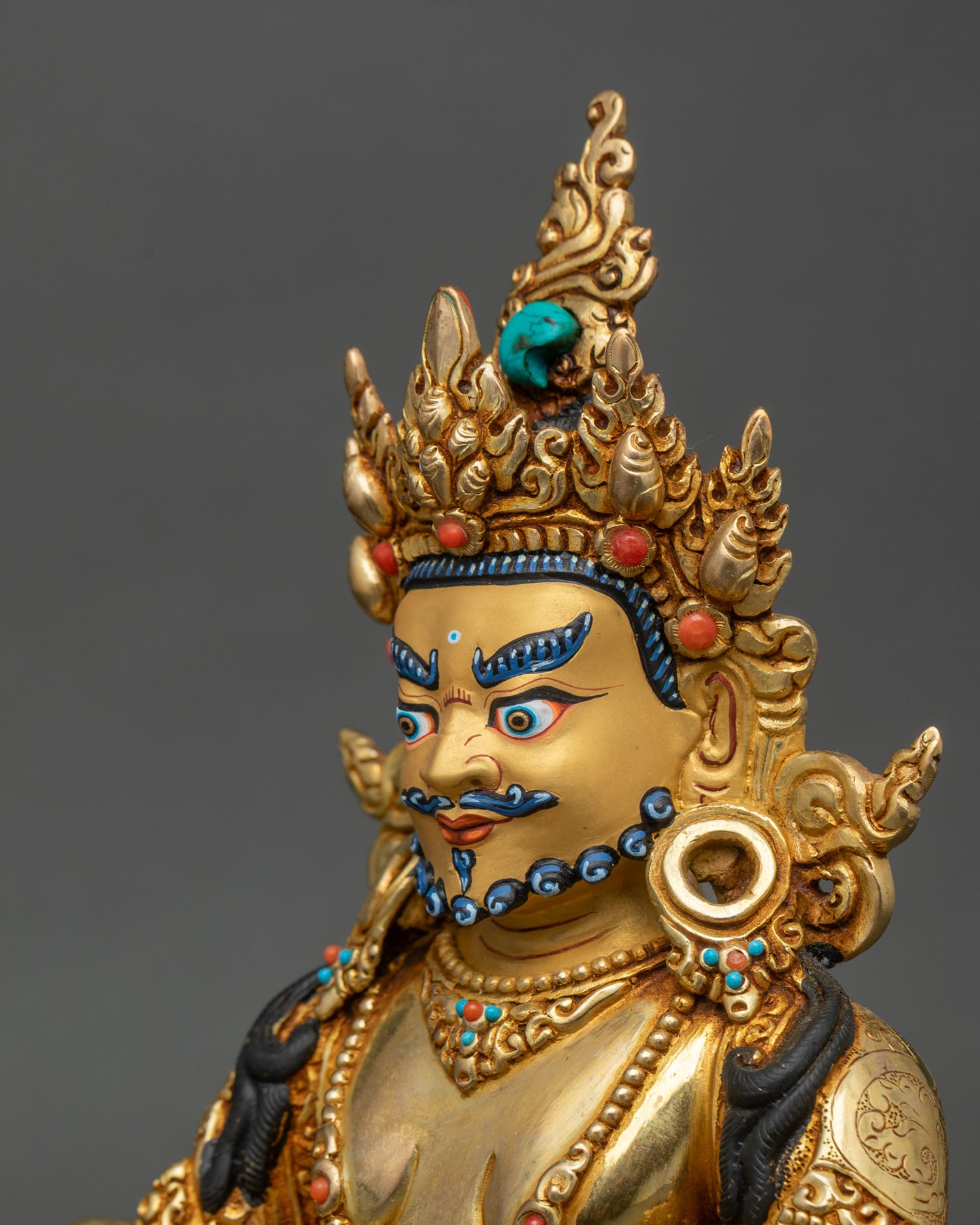 Side close-up of Dzambhala statue highlighting turquoise and coral inlaid halo work
