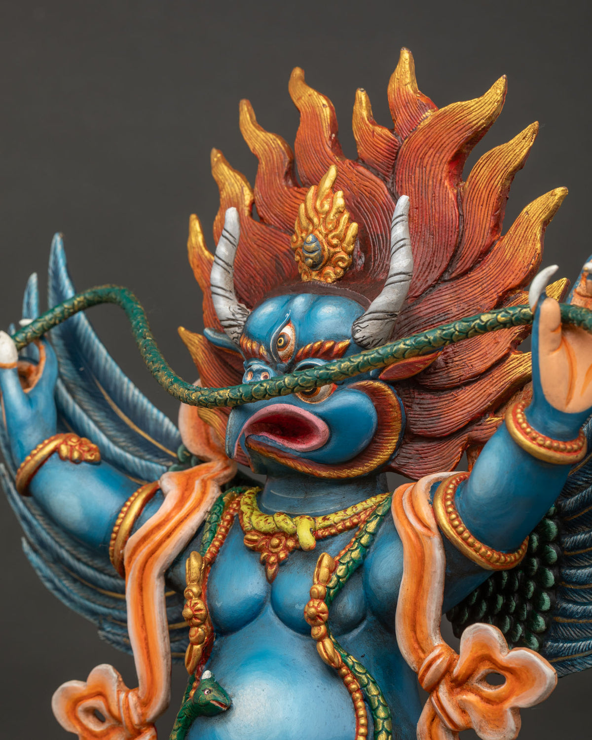 Side close up of Garuda statue showing feather texture and robes