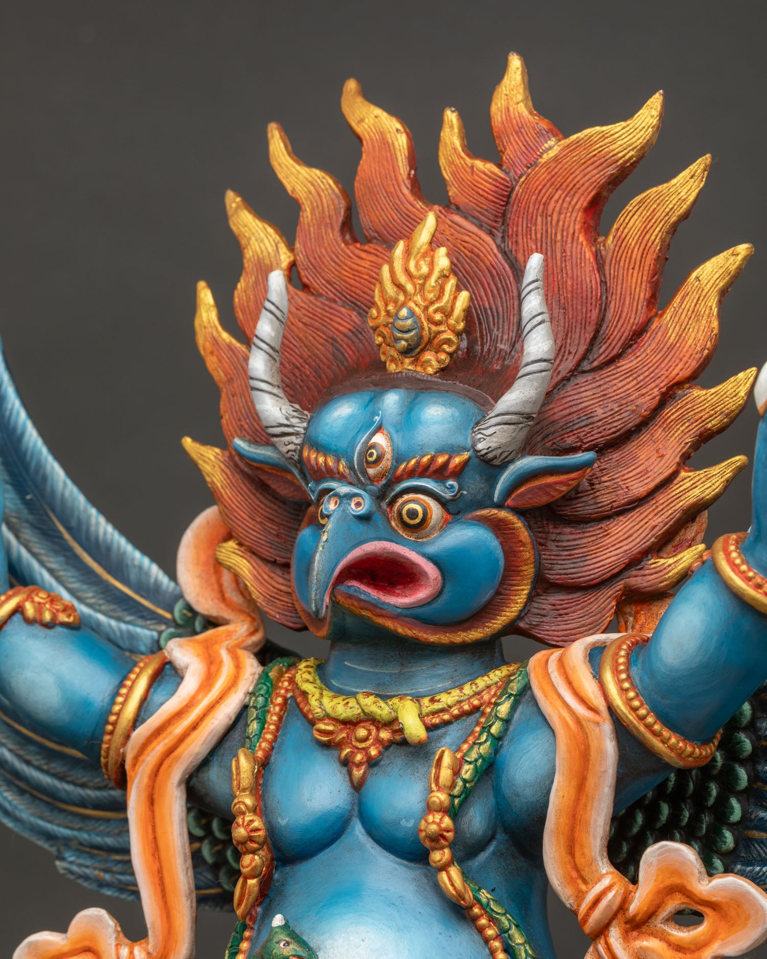 Side close up of Garuda's face showing flame crown and expression