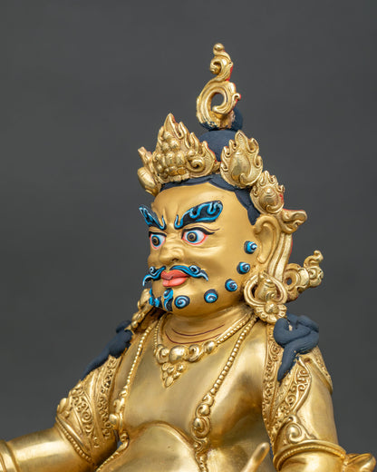 Side close up of gold gilded Dzambhala statue with engraved robes, jewelry and flame-shaped crown