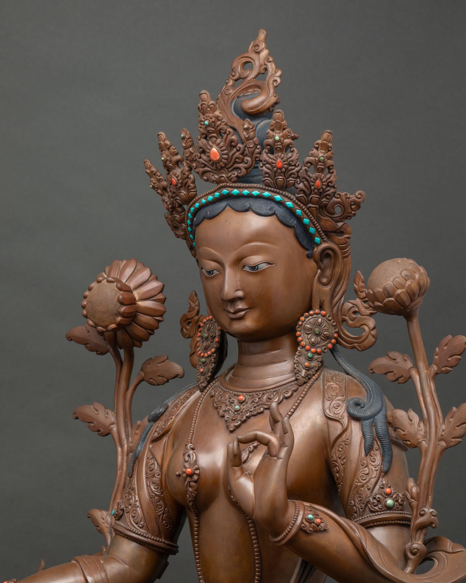 Side close-up of Green Tara statue showing intricately carved copper jewelry