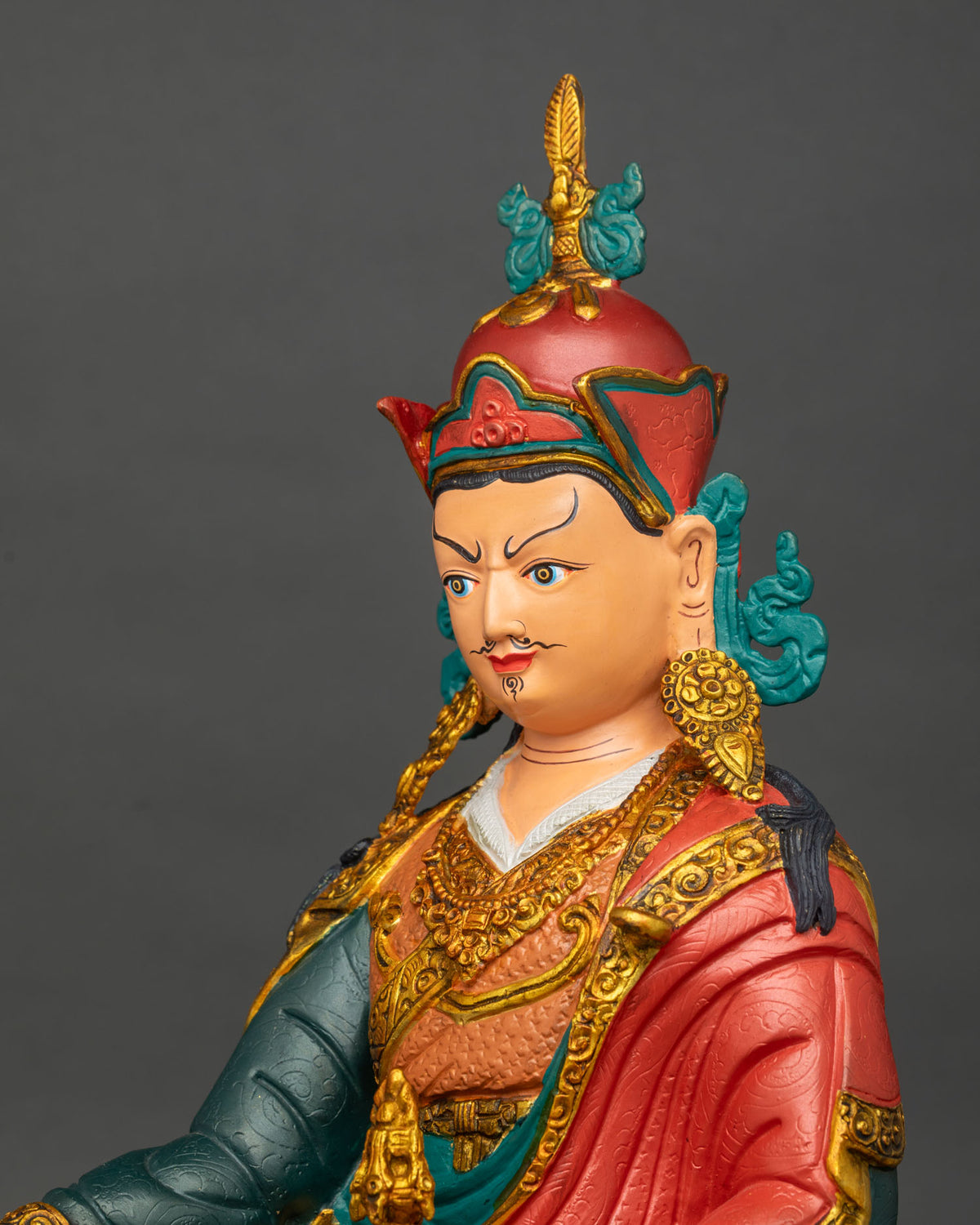 Side close up of Guru Rinpoche statue showing hand-carved robe details and gold gilding, Nepal