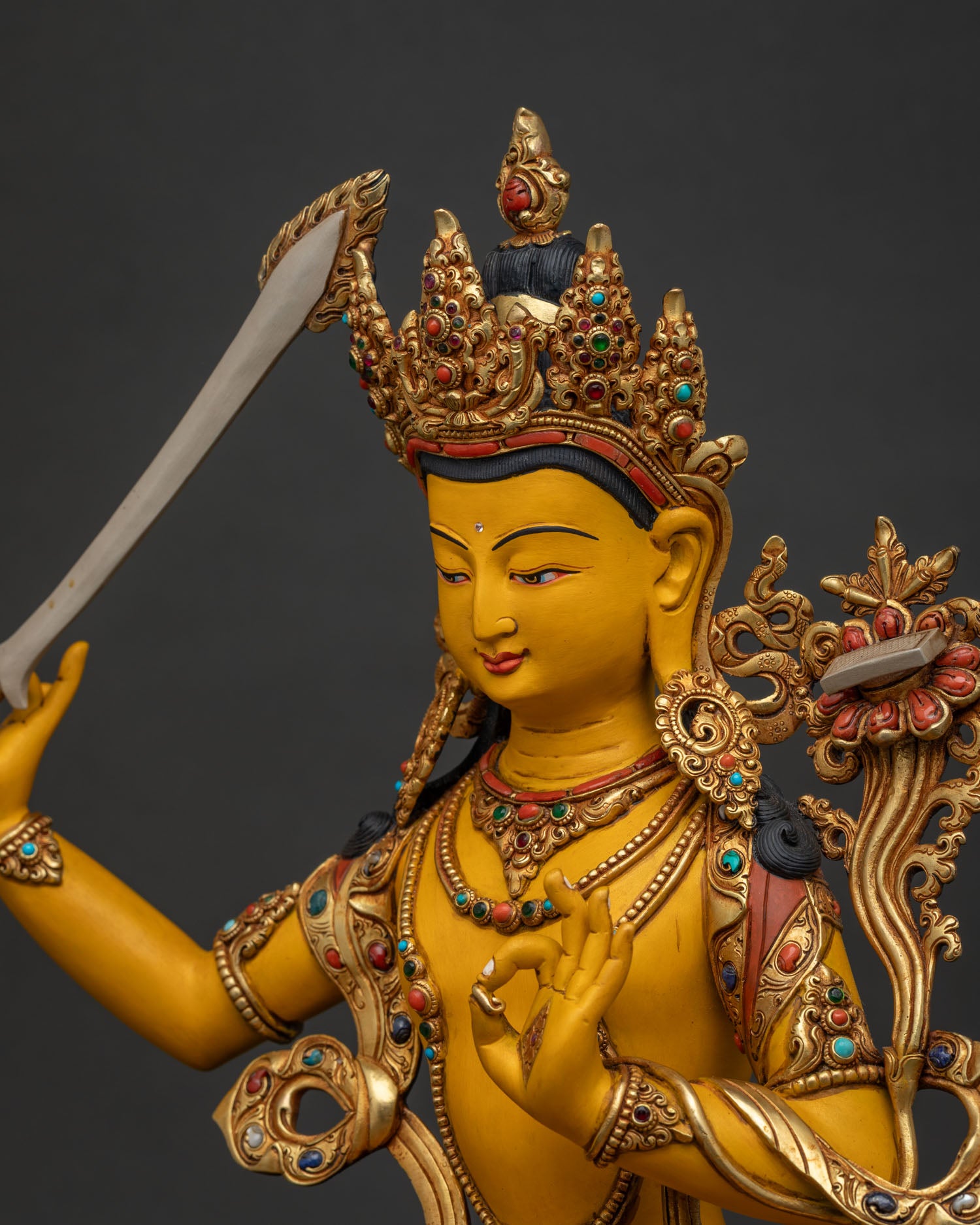 Side close-up of Manjushri statue highlighting hand-carved crown and sword detailing