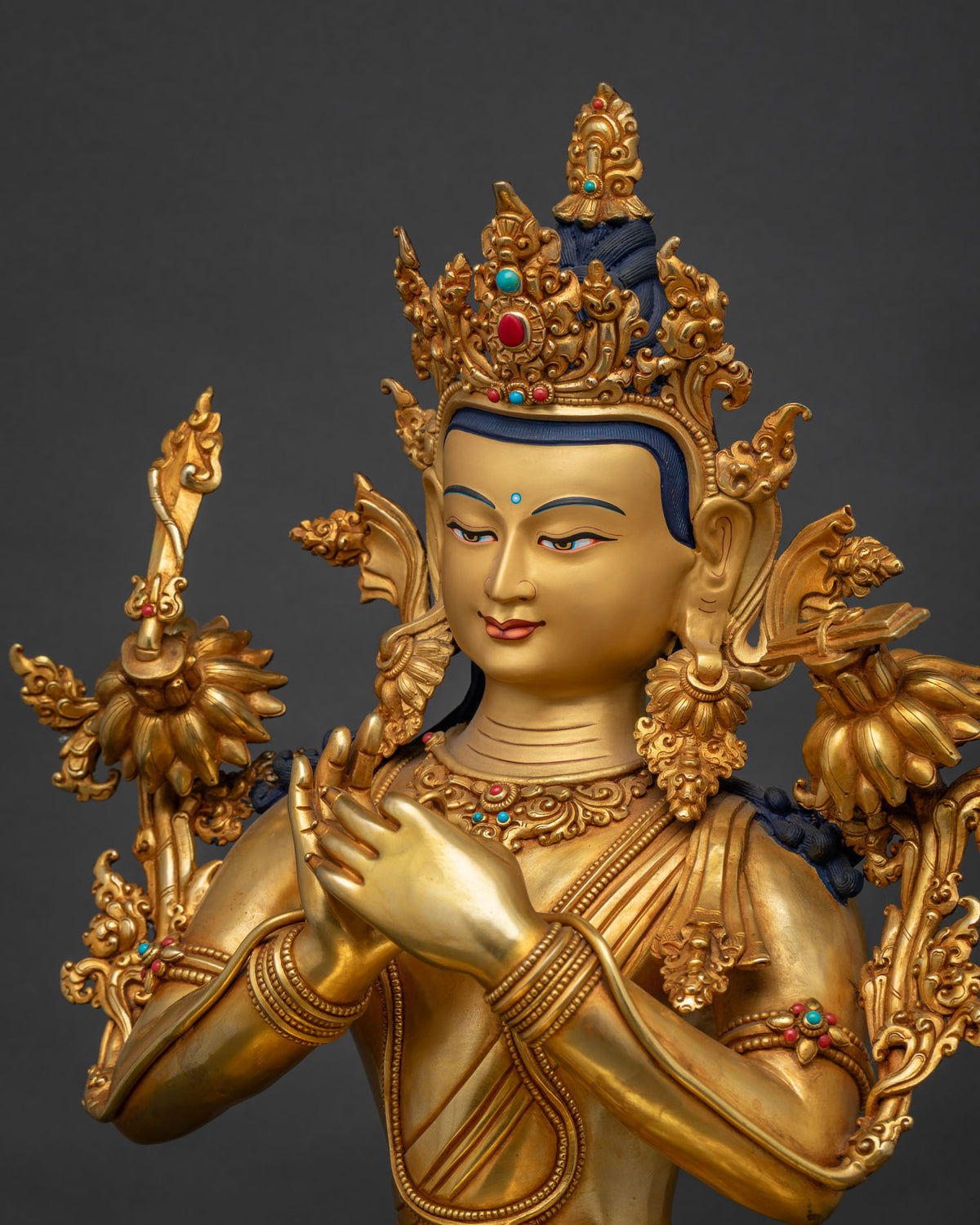 Side close-up of Manjushri statue's crown, shoulder flowers, and hand detail