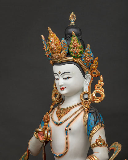 Side close-up of Vajrasattva statue showing vajra, bell and lotus pedestal detail