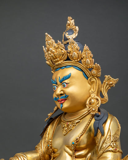 Side close up view highlighting intricate gold chasing and gemstone inlays on Dzambhala sculpture.