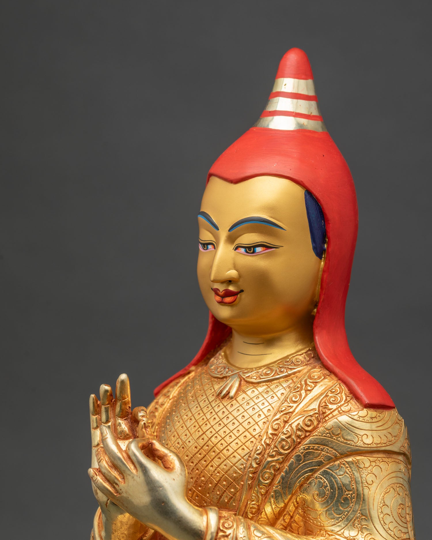 Side detail close up of Atisha statue showing engraved robes and lotus pedestal