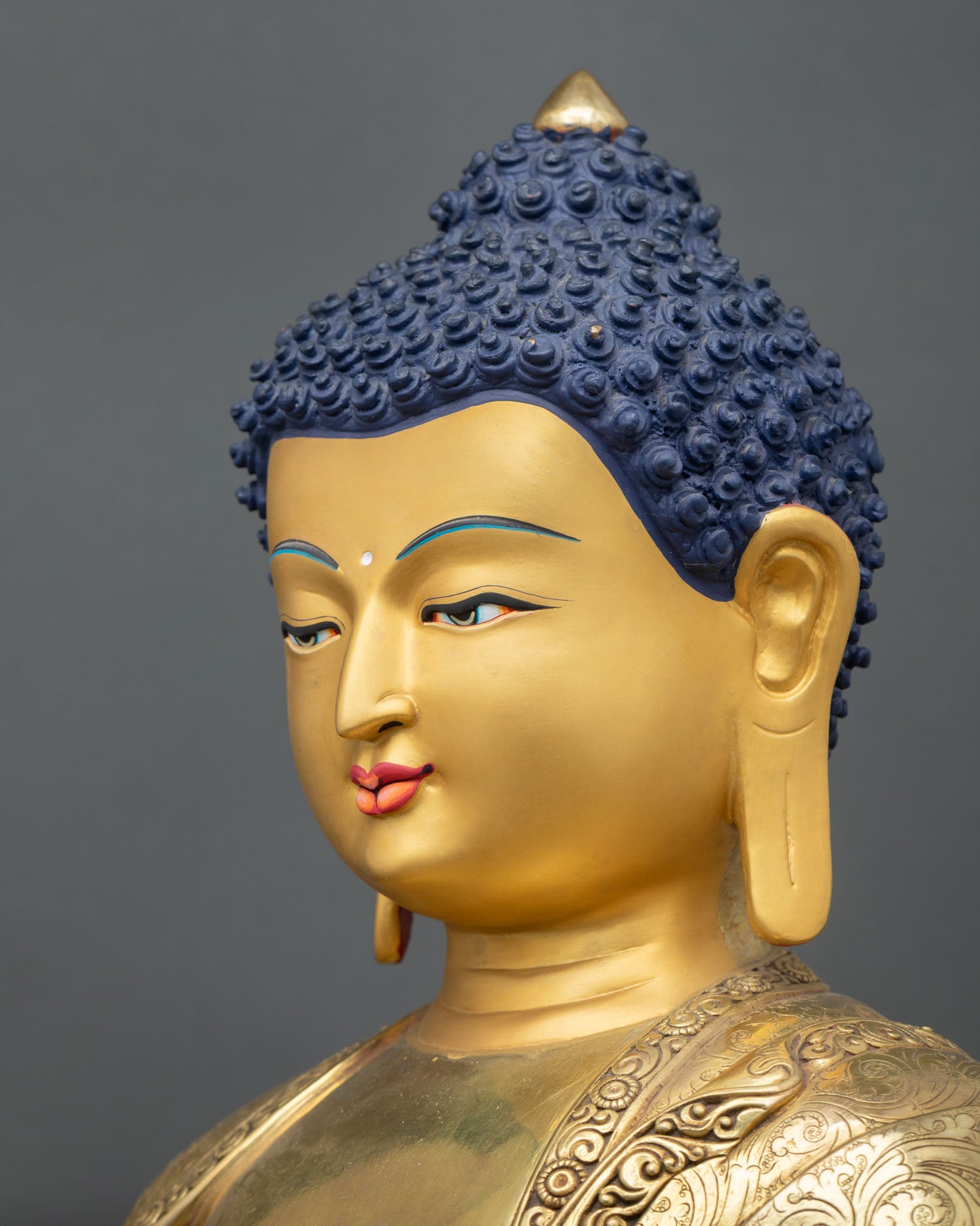 side face close-up of shakyamuni buddha statue with peaceful eyes and gold detailing