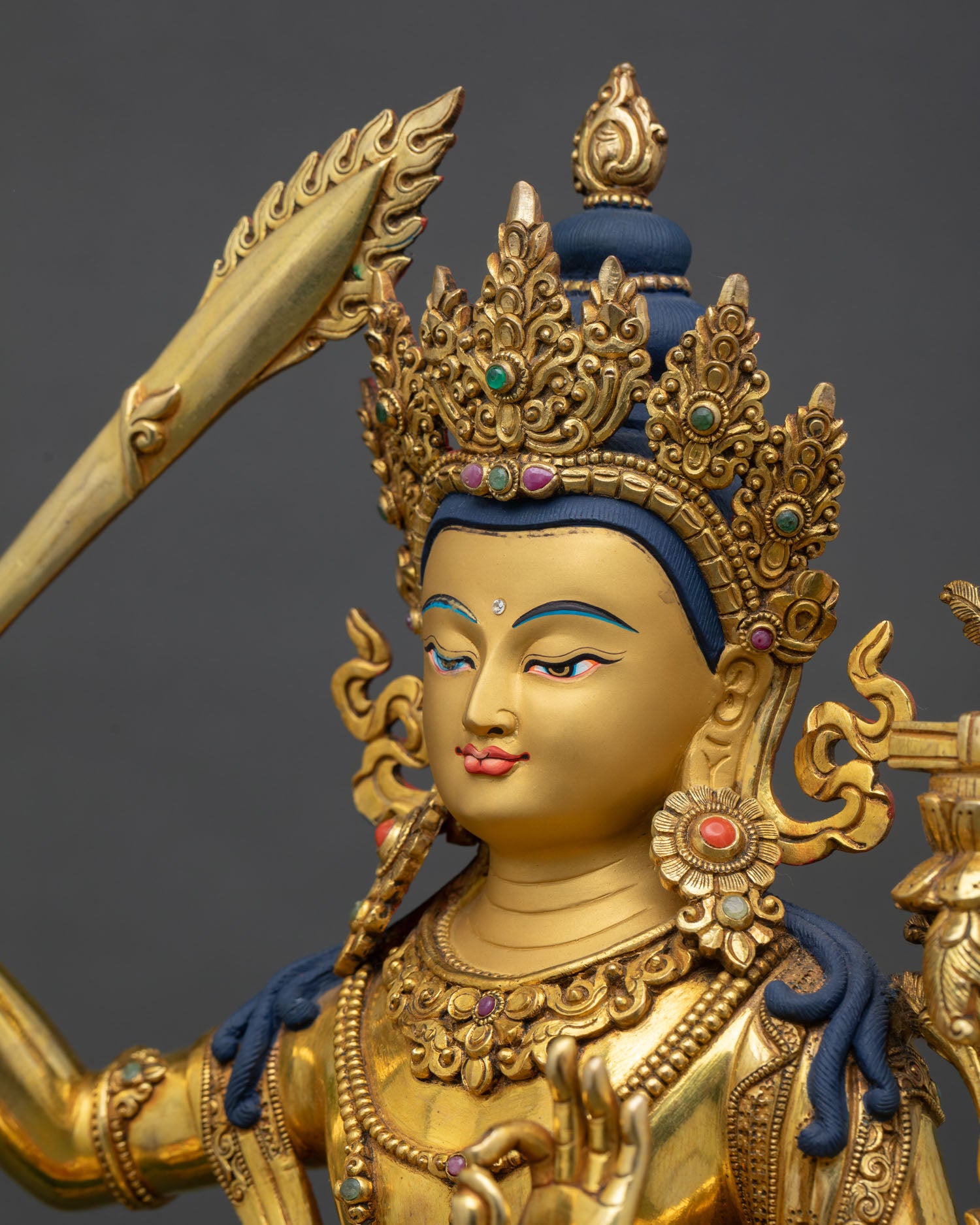 side portrait detail of manjushri face, golden features and finely carved crown elements