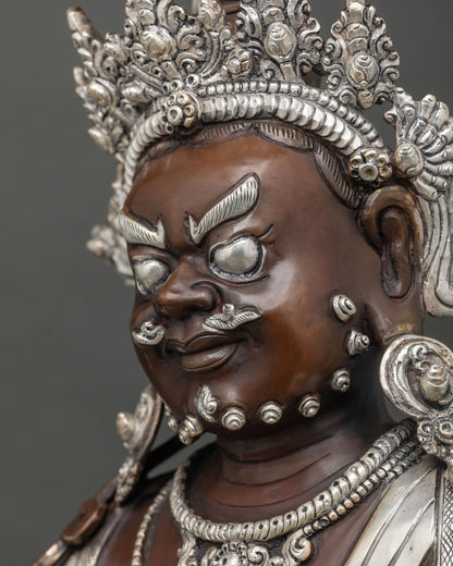 Side profile close up of Dzambhala statue face with silver crown and carved ornaments