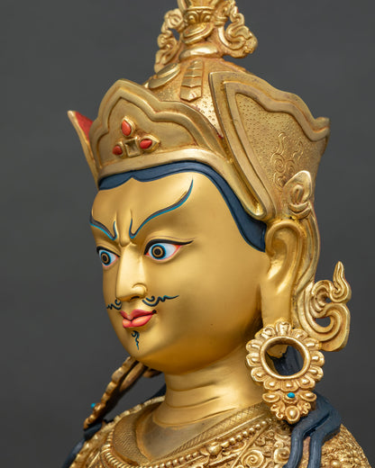 Side profile close up of Guru Rinpoche statue face, gold-painted with mustache and feathered lotus hat
