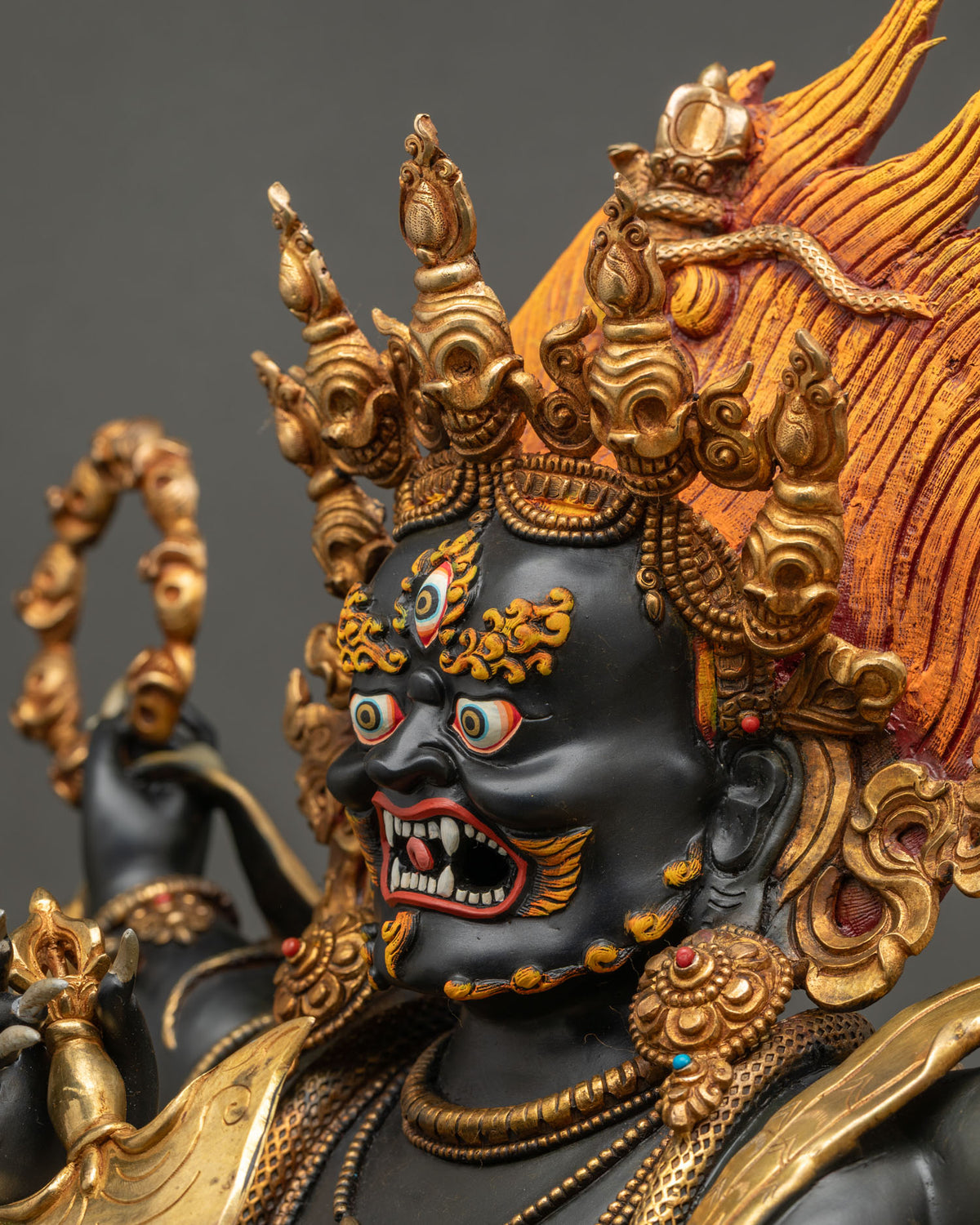 Side profile close up of wrathful Black Mahakala face with fierce fangs and flaming hair, Nepal