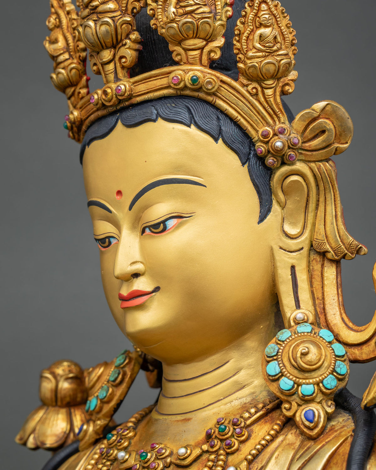 Side profile of Green Tara statue showing serene face, turquoise earrings and carved gold crown