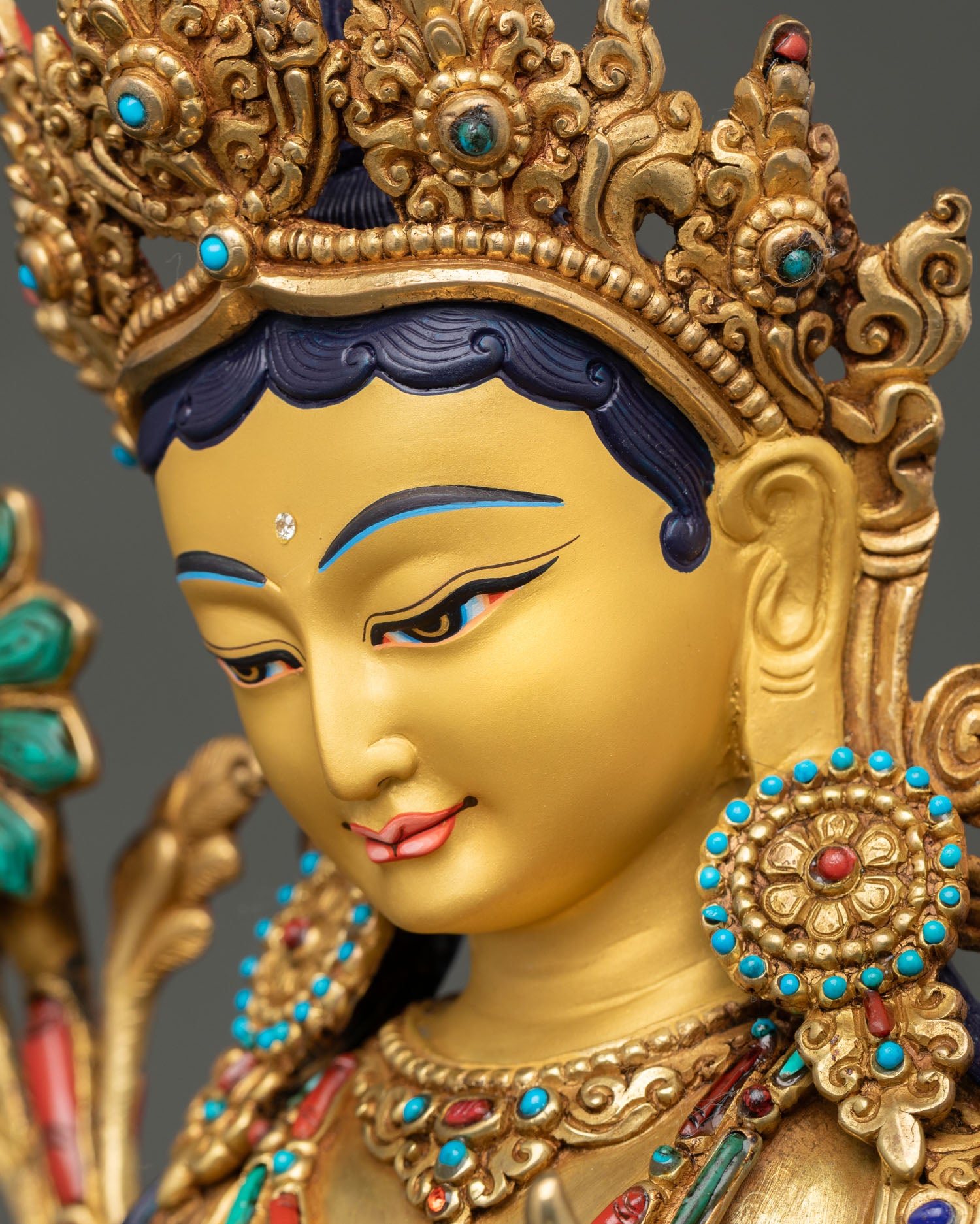 Side profile of Green Tara with gold-painted face and ornate crown