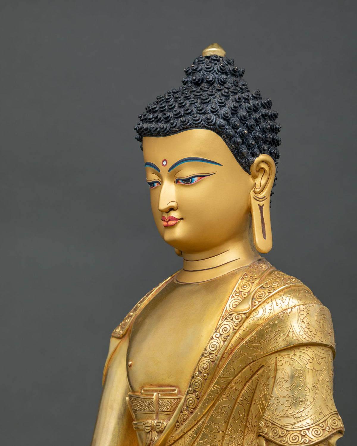 Side profile of Nepalese Shakyamuni Buddha statue with curled hair, ushnisha and gold-painted face