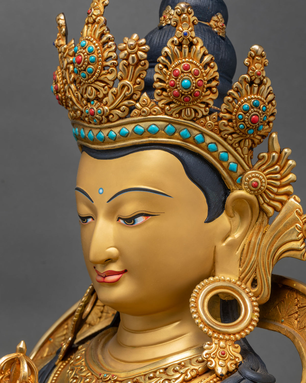 Side profile of Vajrasattva statue face with downcast eyes, jeweled five-pointed crown and earrings