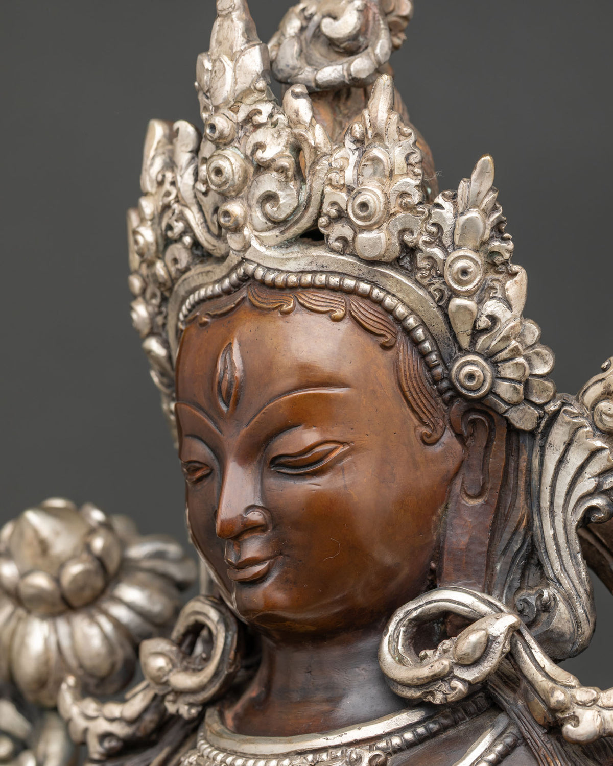 Side profile White Tara statue face with crown and Himalayan artisan metalwork