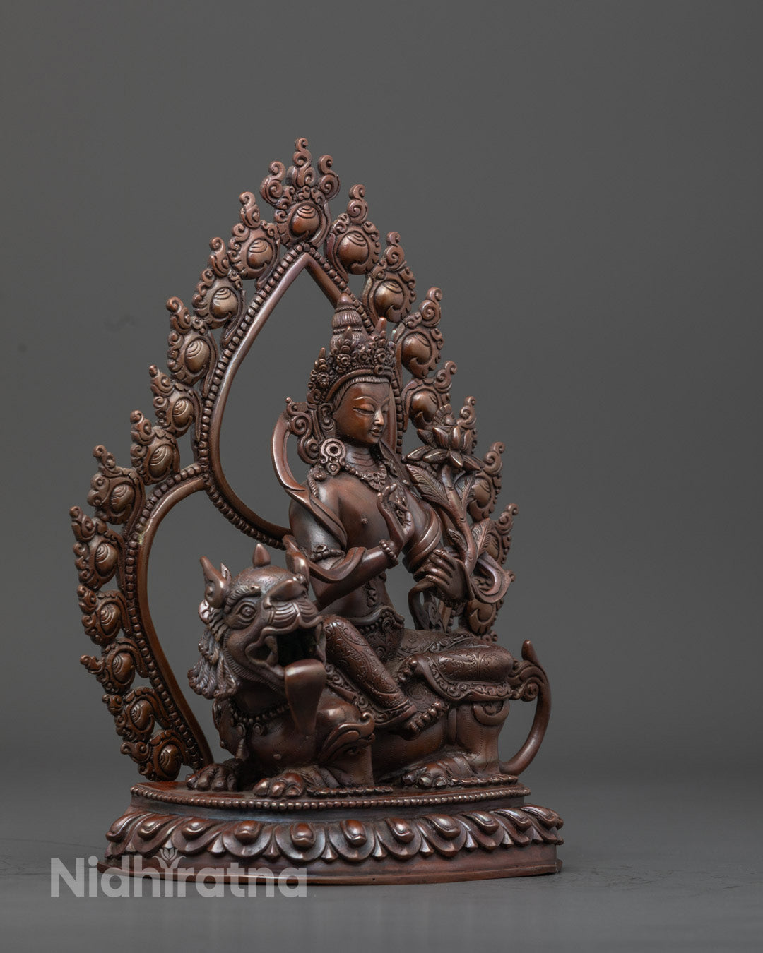 Side view of Chenrezig statue in seated posture, oxidized copper sculpture