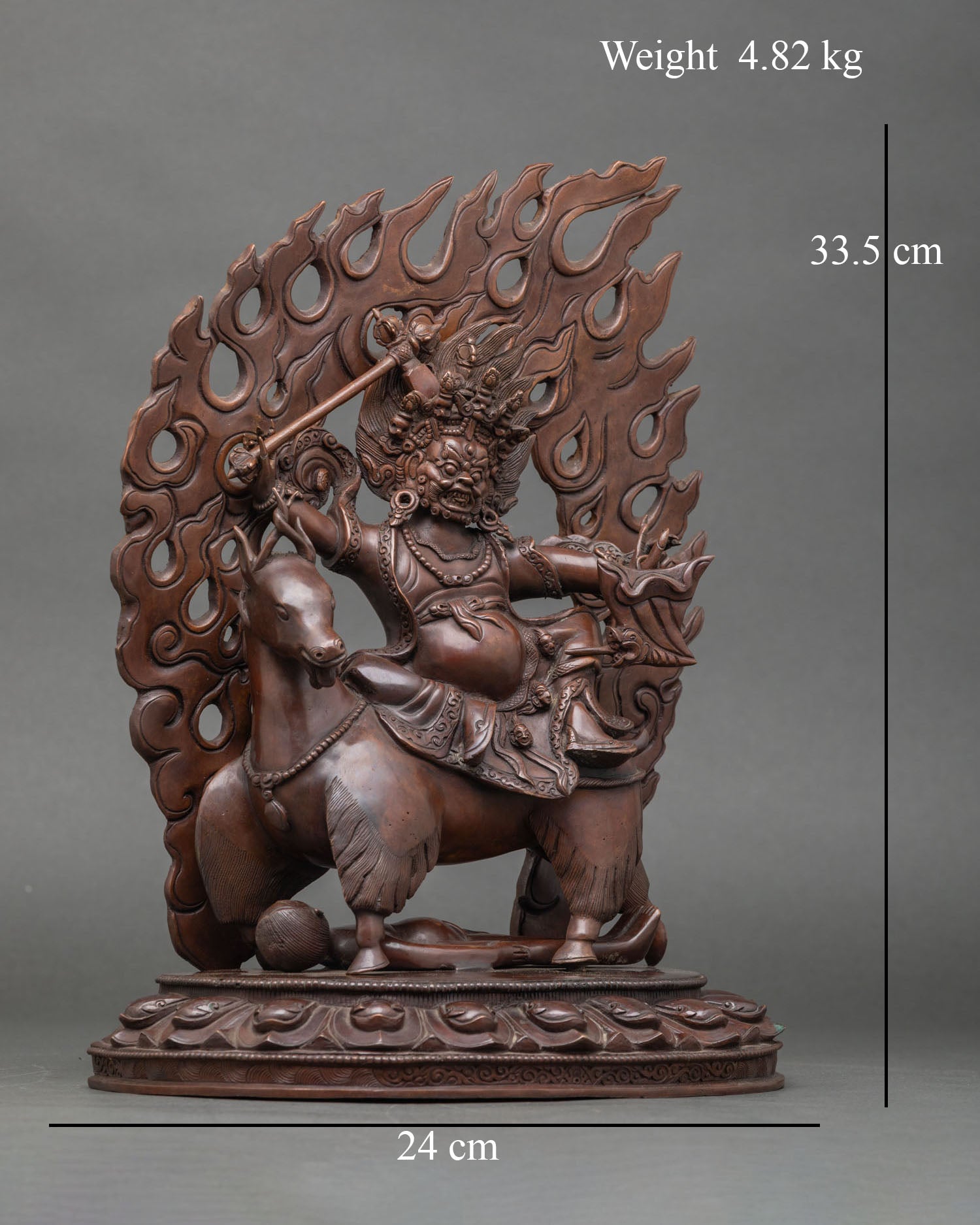 Side view of Dachhen Garwa Nagpo statue holding hammer and bellows seated on twisted horn goat flaming halo protection energy