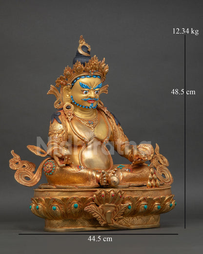 Side view of Dzambhala statue, copper body, gold gilded finish, seated posture, wealth god holding symbolic objects
