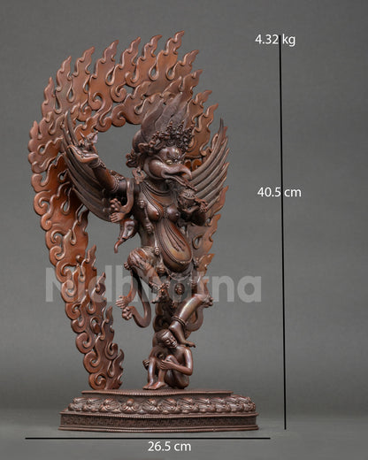 Side view of Garuda statue standing over subdued figure symbolic victory over negativity Nepalese metal art sculpture