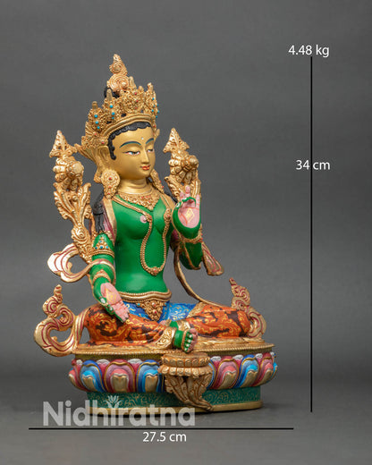 Side view of Green Tara statue holding a blooming utpala flower on lotus seat