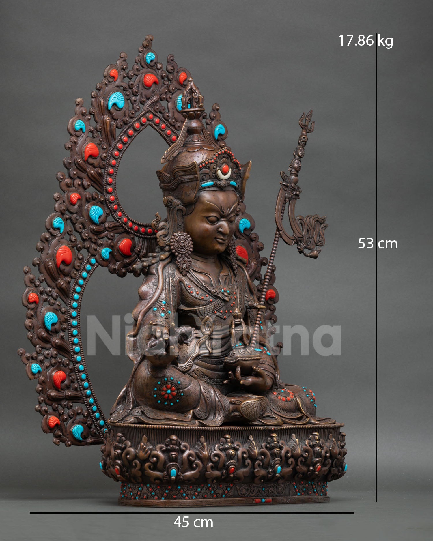 Side view of Guru Rinpoche Buddhist statue holding vajra and kalash with trident on shoulder