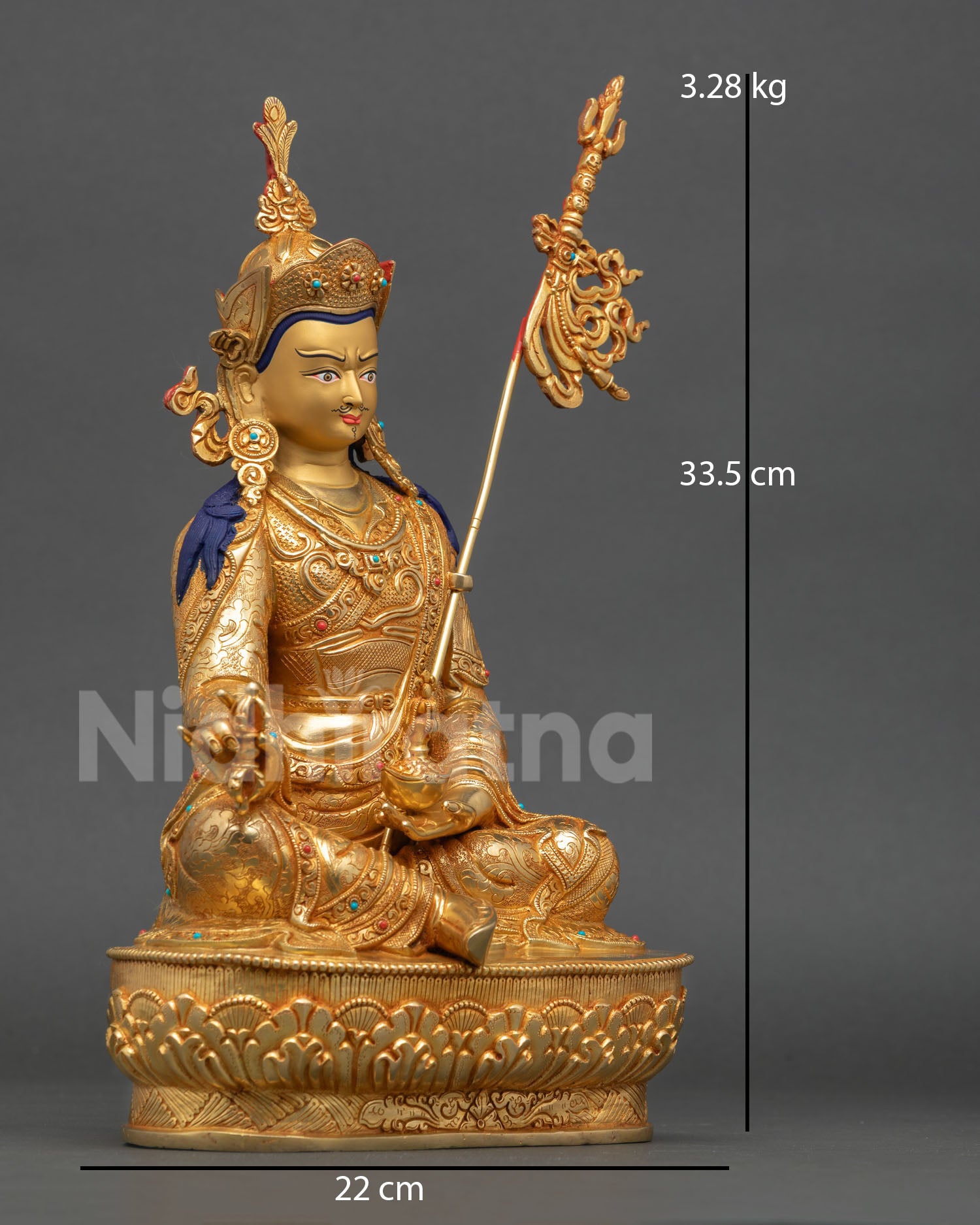 Side view of Himalayan Guru Rinpoche copper statue holding khatvanga staff with vajra symbol and ornate detailing
