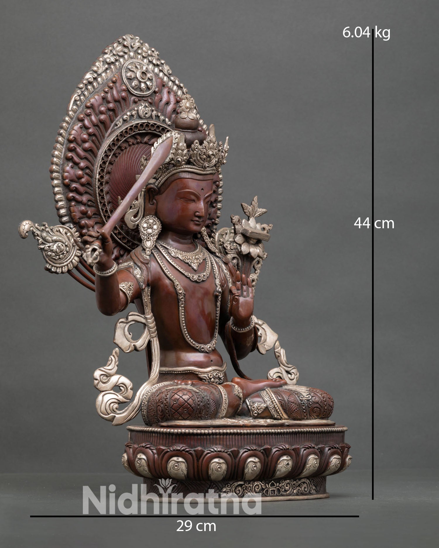 Side view of Manjushri statue holding flaming sword of wisdom symbolizing cutting ignorance, Buddhist altar sculpture with oxidized finish