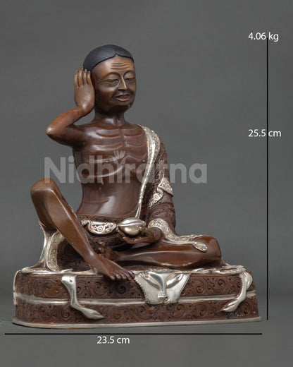Side view of Milarepa sculpture, holding a skull cup, symbolizing spiritual awakening and transcendence over worldly attachments