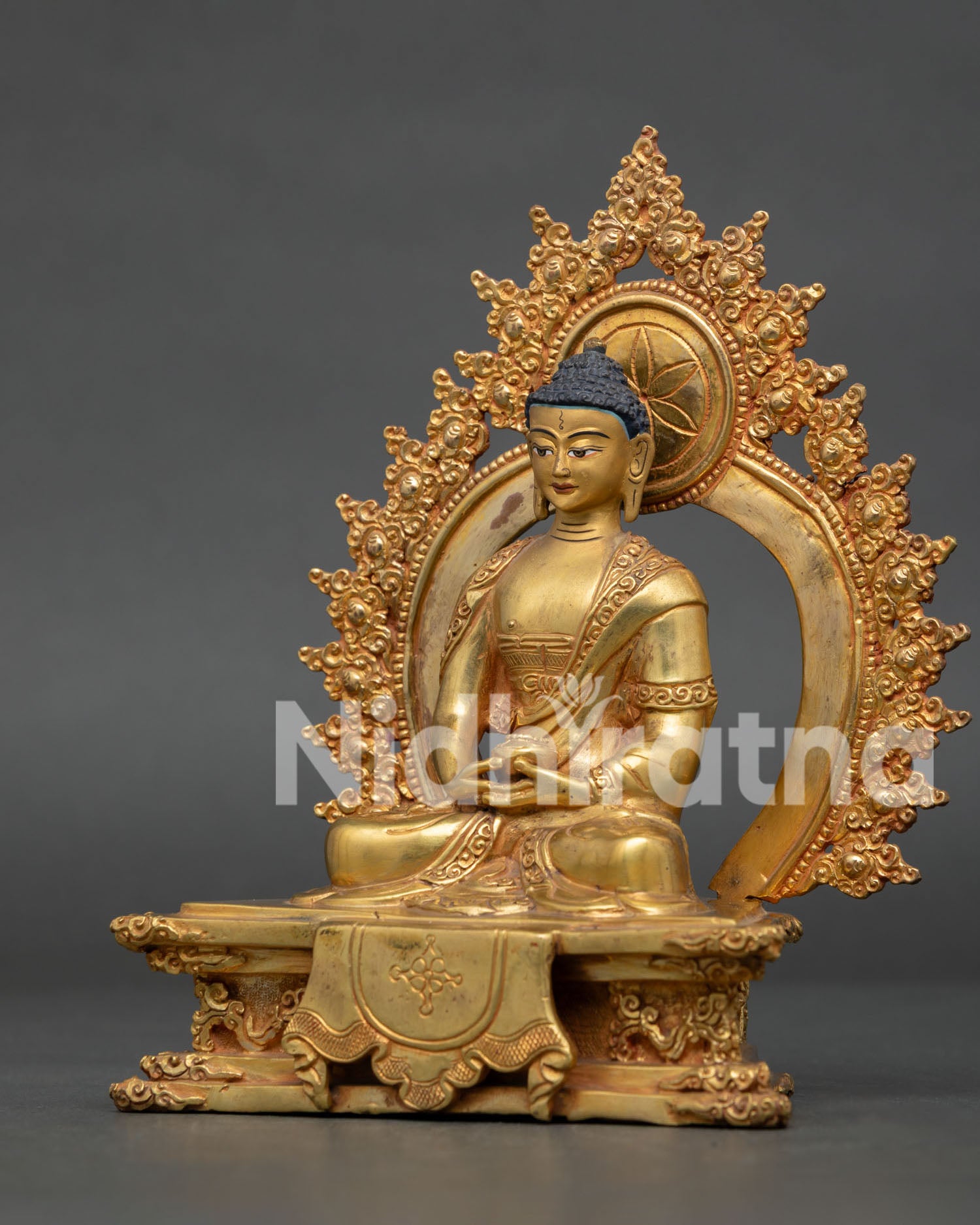 Side view of Amitabha Buddha on ornate royal throne with gold gilded copper finish.