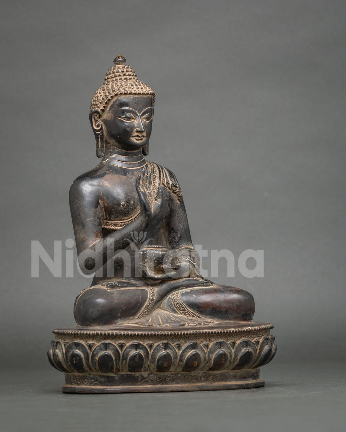Side view of Amoghasiddhi Buddha statue showing monastic robe, lotus pedestal and bowl in left hand