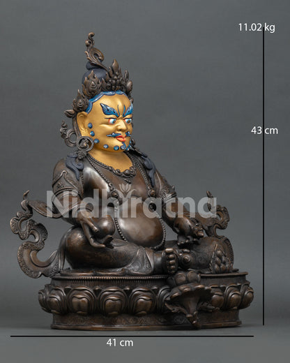 Side view of copper Jambhala Buddhist statue with oxidized finish and sacred details