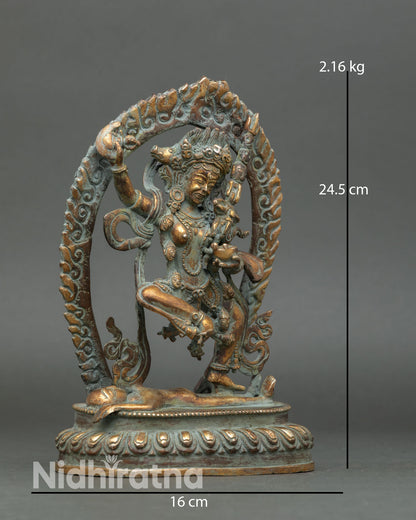 Side view of Dorje Phagmo statue holding curved kartika and kapala with khatvanga staff on shoulder surrounded by radiant flames