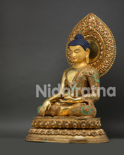 Side view of gold Shakyamuni Buddha statue seated on tiered lotus pedestal