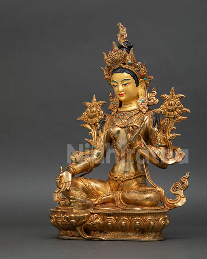 Side view of Green Tara statue adorned with coral and turquoise gemstones.