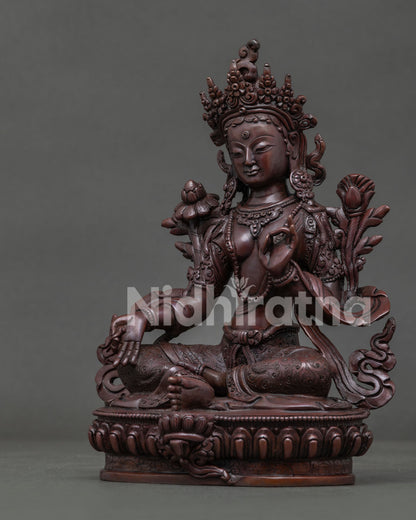 Side view of Green Tara statue showing flowing scarf and extended right leg on lotus throne.