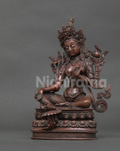 Side view of Green tara statue with extended right leg and handcarved double lotus pedestal.