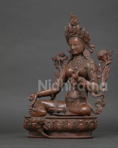 Side view of Green Tara Statue with extended right leg blooming lotus and sacred ornaments Nepal.