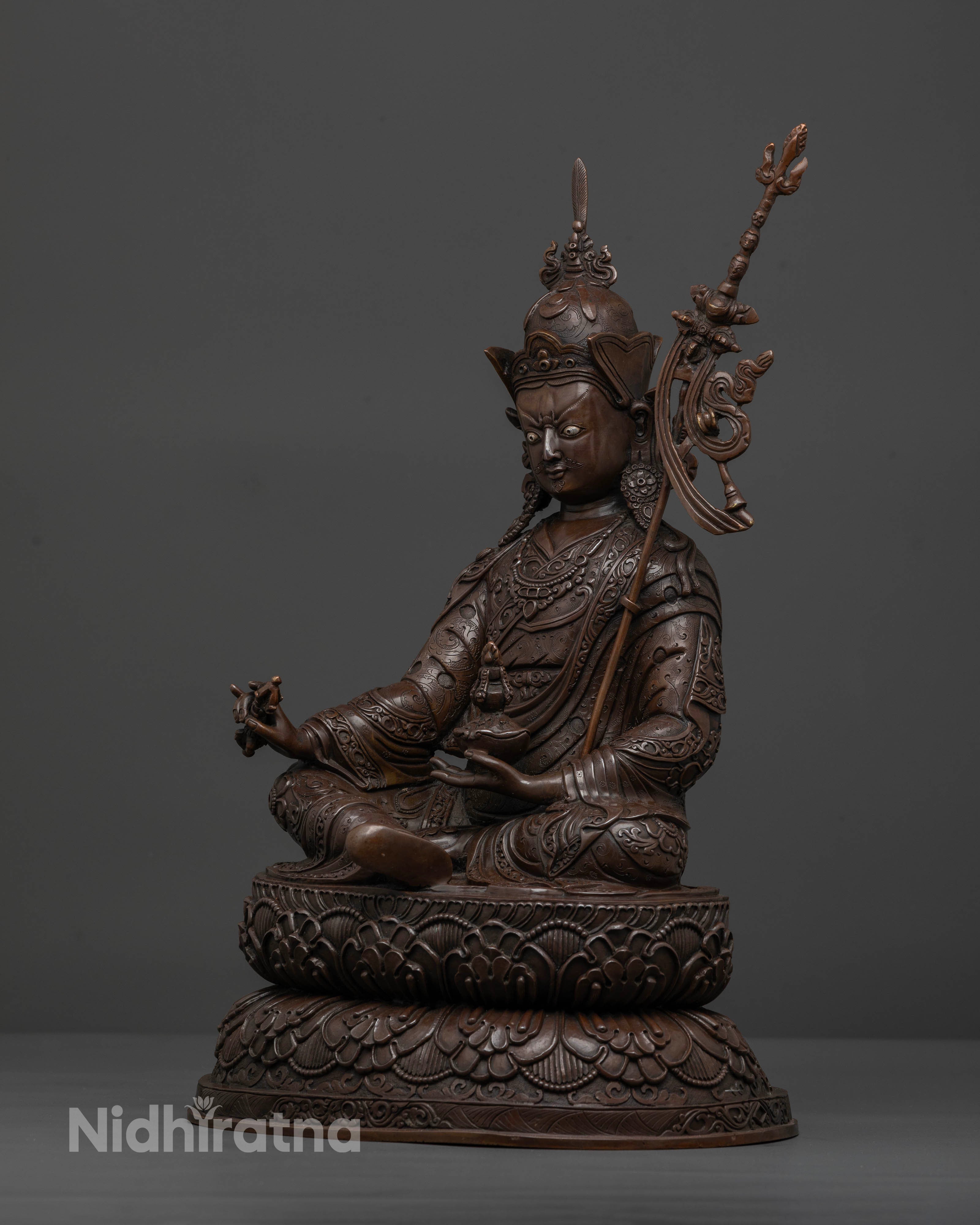 Side view of Guru Rinpoche statue with khatvanga and intricate Buddhist carvings