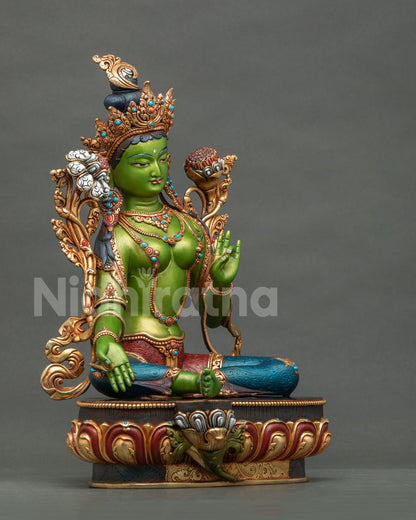 Side view of hand-painted Green Tara statue showing gold crown, jewelry and lotus base