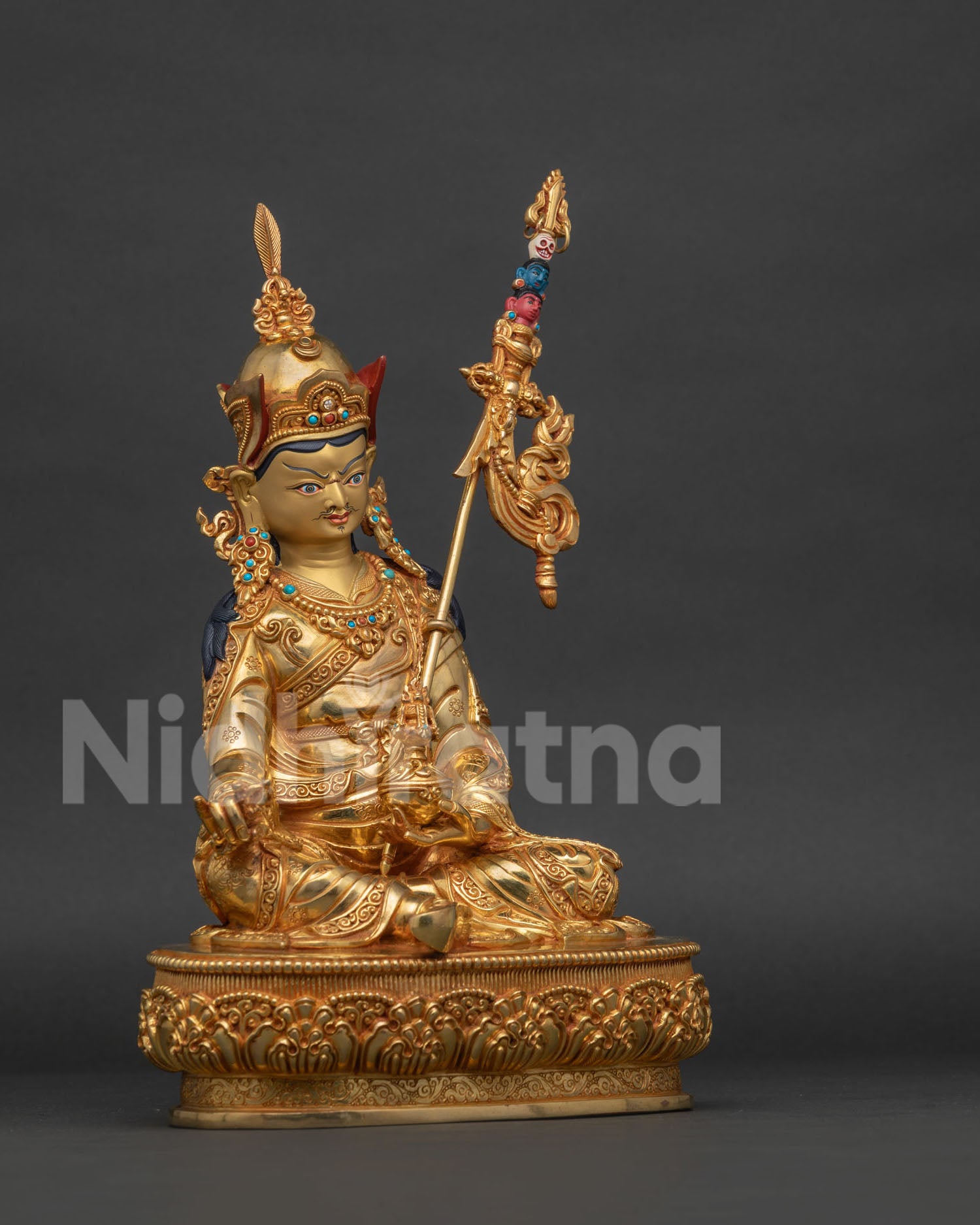 Side view of handcrafted Guru Rinpoche statue with skull cup vajra and gold gilded details.