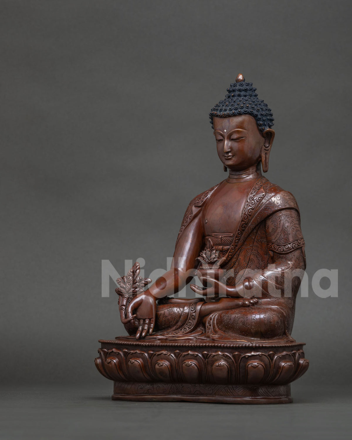 Side view of handcrafted Medicine Buddha statue seated on lotus pedestal.