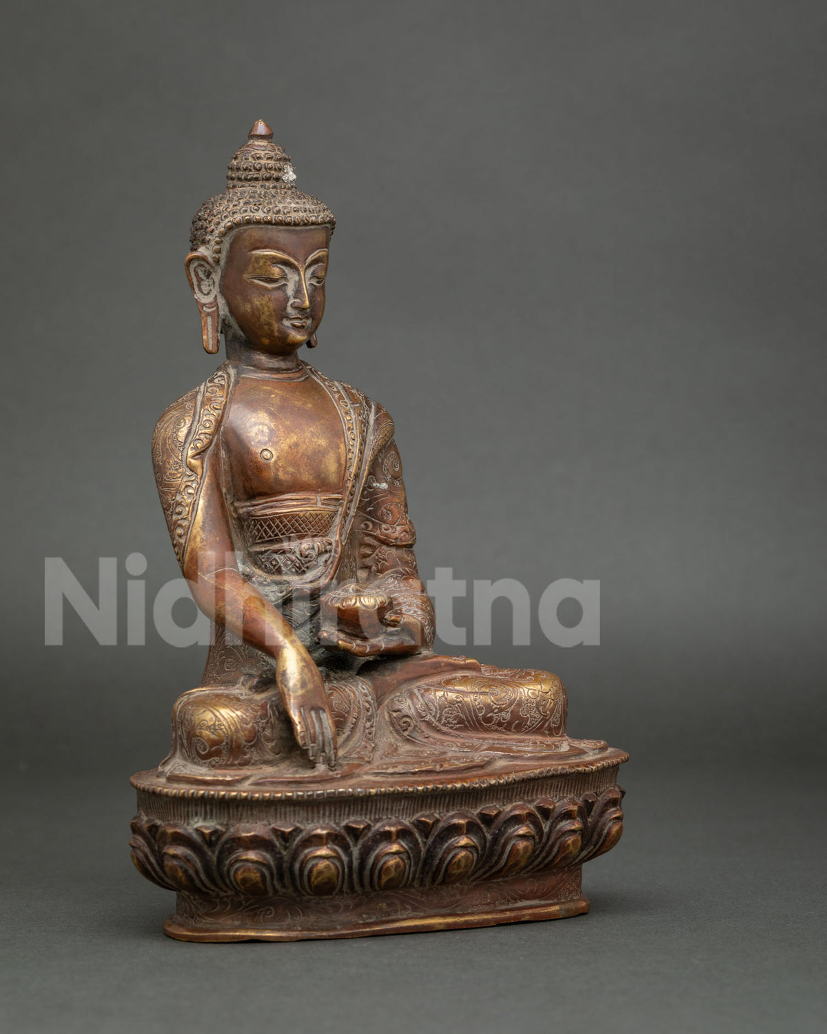 Side view of handcrafted Shakyamuni Buddha statue seated on a traditional lotus pedestal.