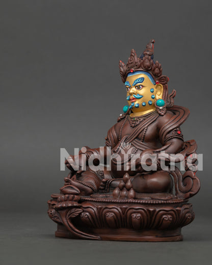 Side view of handmade Dzambhala statue showing lotus throne, mongoose, and flowing robe details.