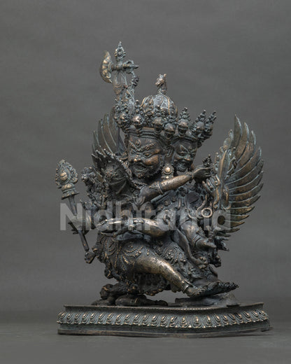 Side view of handmade Hayagriva bronze statue trampling a demon on an ornate lotus base