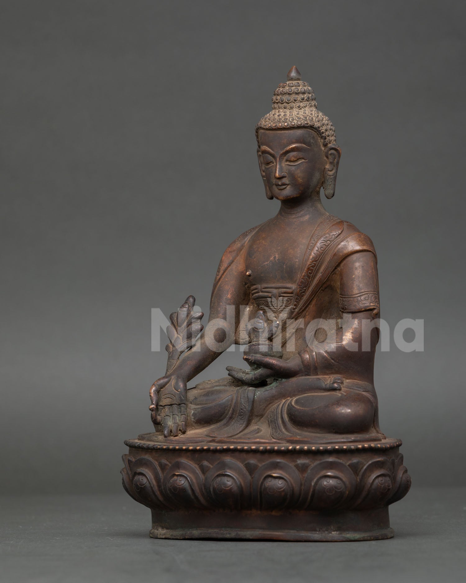 Side view of Medicine Buddha statue on lotus pedestal handcrafted in Nepal from copper.