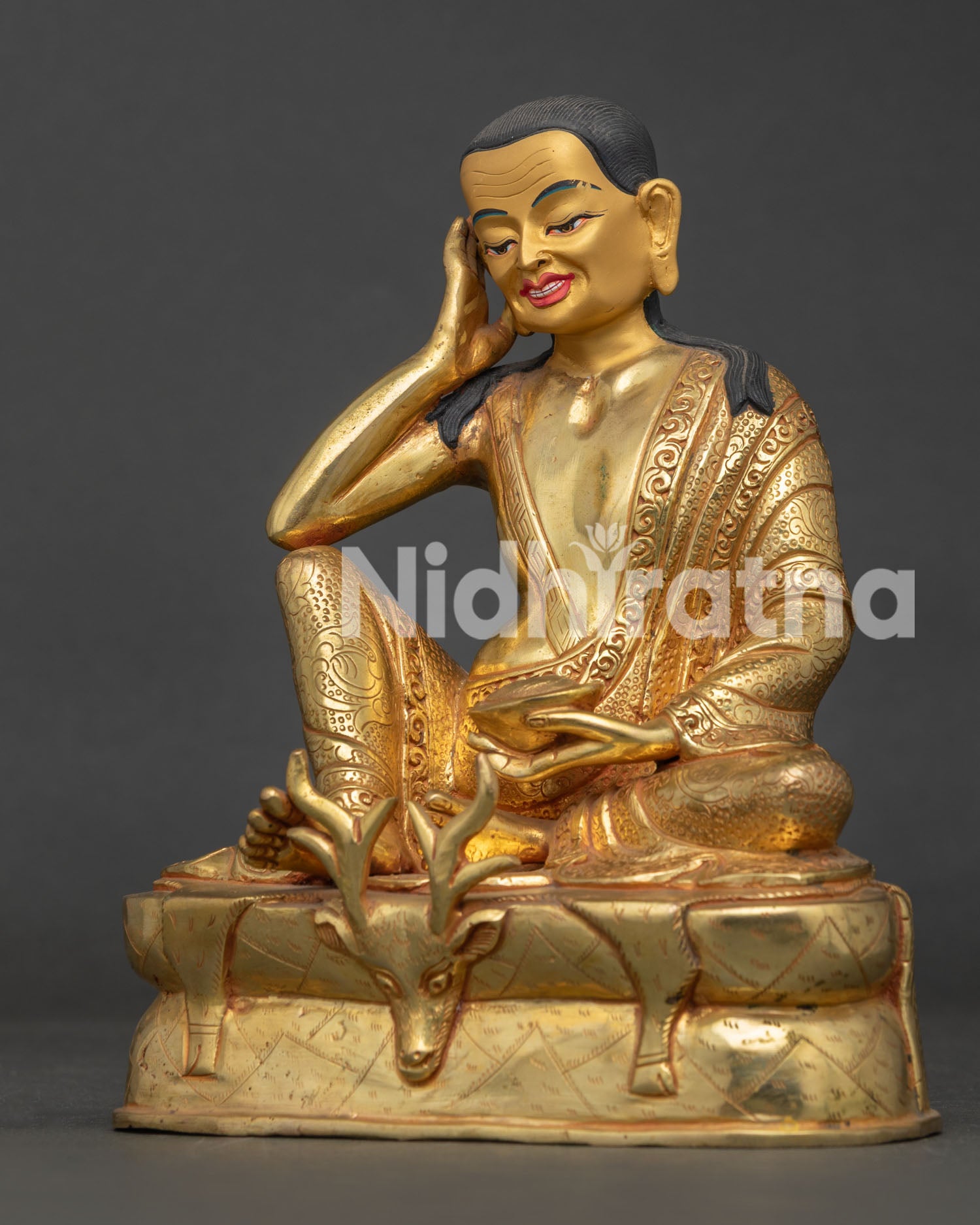 Side view of Milarepa statue showing crossed legs deer skin pedestal and intricate carvings.